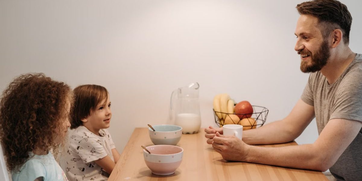 A father having a warm conversation with his children during breakfast at home.