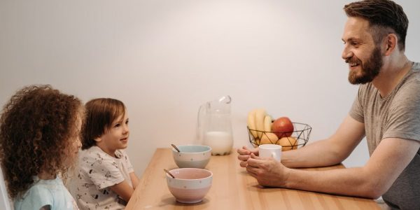 A father having a warm conversation with his children during breakfast at home.